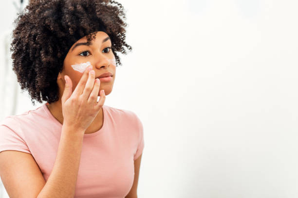 istock Young woman applying moisturizer cream on her face 1137095234