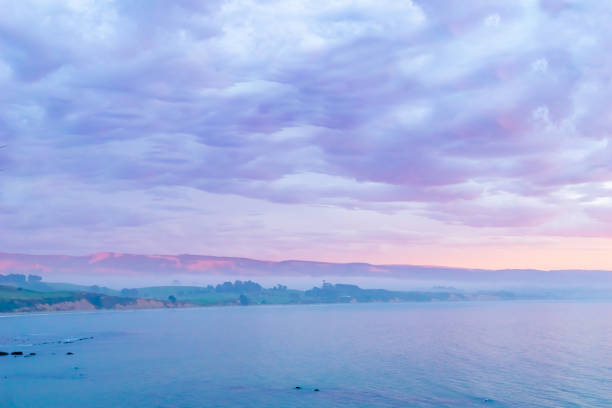 Cumulus cloud formation above sea and hills in coastal New Zealand
