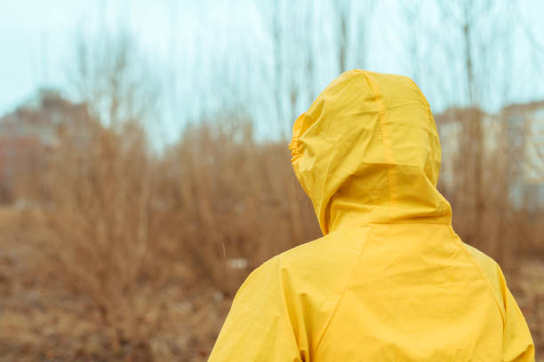 blick auf frau im regenmantel in die ferne - drenched raincoat rain clothing stock-fotos und bilder