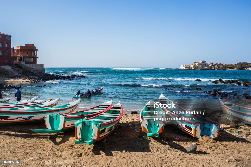 A bay in Ngor, Dakar. Fishing boats in Ngor Dakar, Senegal, called pirogue or piragua or piraga. Colorful boats used by fishermen standing in the bay of Ngor on a sunny day. Senegal Stock Photo