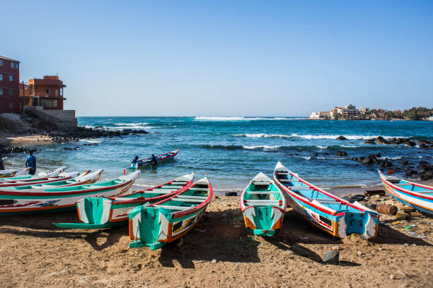 A bay in Ngor, Dakar. Fishing boats in Ngor Dakar, Senegal, called pirogue or piragua or piraga. Colorful boats used by fishermen standing in the bay of Ngor on a sunny day. senegal beach stock pictures, royalty-free photos & images