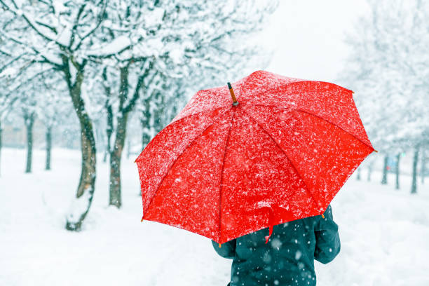 istock Woman with red umbrella standing in snow 1137099252