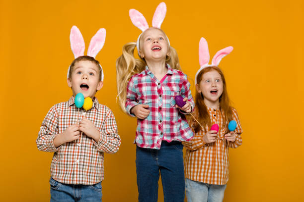 istock two little girls and boy with Easter bunny ears holding colorful eggs 1137100177