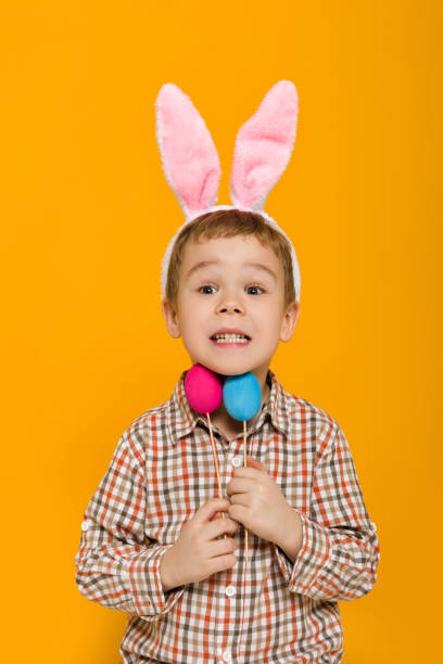 istock little child boy with Easter bunny ears holding colorful eggs 1137100829