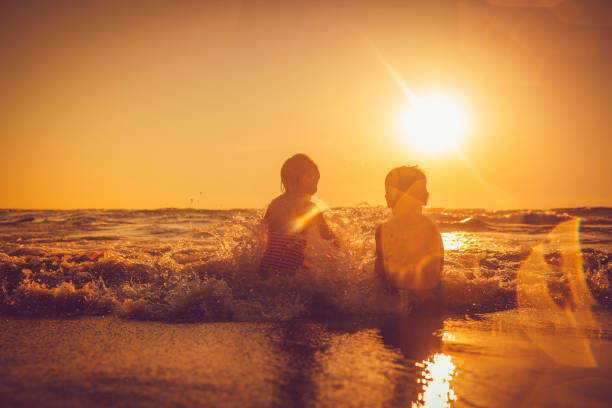 istock Children swimming and having fun at sea waves at sunset 1137102926