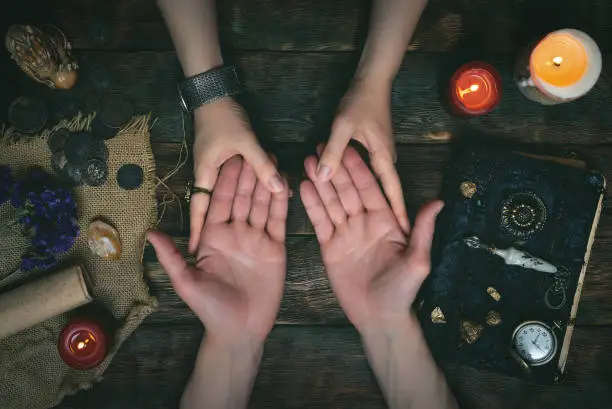 Palmistry concept. Fortune teller reading future on the hand on a magic table background. Future reading concept.