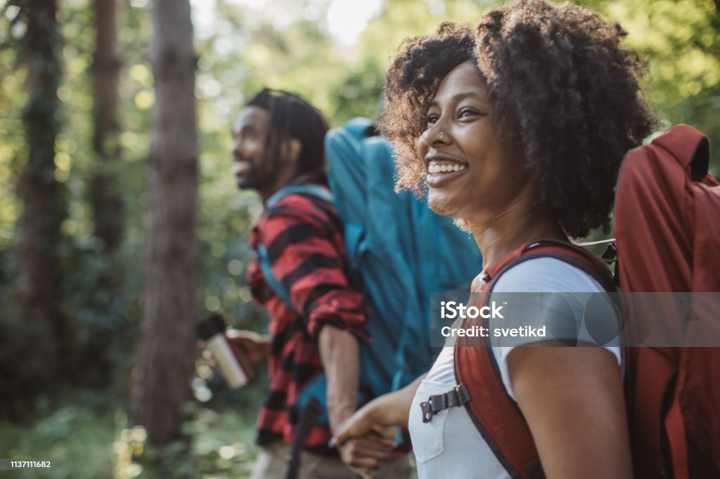 Hor drink on forest walk Young couple on vacation in countryside, they enjoy in summer. They walking through forest, exploring nature and drinking hot coffe from travel mug Hiking Stock Photo