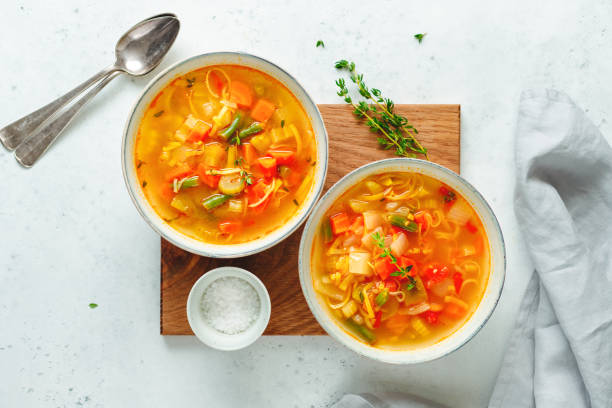 istock View from above on spring vegetable soup with chicken stock for two person on white table. 1137115506