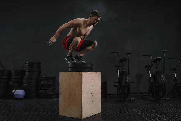 istock cross training box jump exercise. Athlete jumping onto the box 1137123978