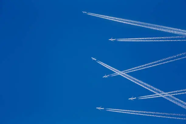 Multiple aircraft in the sky with chemtrail. Conspiracy theory concept. White airliners against blue sky. Photo manipulation.