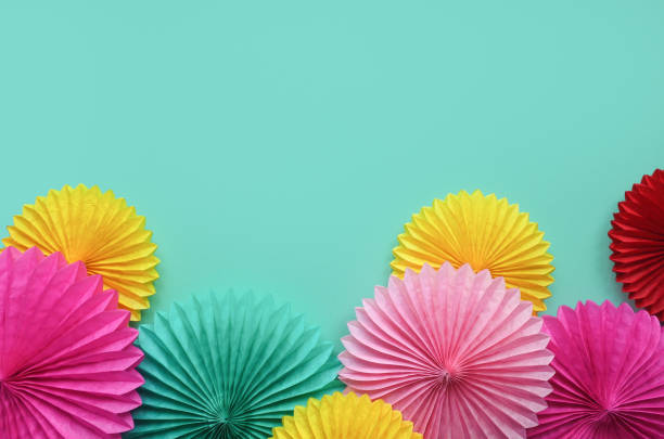 istock Different paper flowers on green table top view. Festive or party background. Flat lay style. Copy space for text. Birthday greeting card. 1137136845