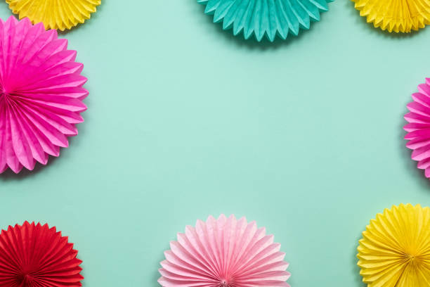 istock Diffrent paper flowers on green table top view. Festive or party background.  Copy space for text. Birthday greeting card. 1137137219