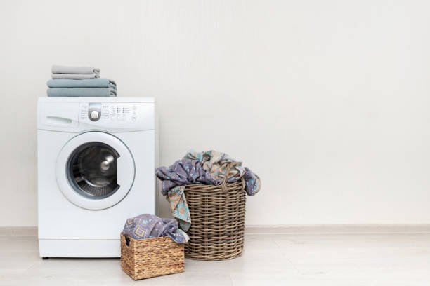 istock Preparation to laundry process. White washing machine with two basket with lien on floor and few towels on top standing isolated inside bright apartment light interior 1137138057