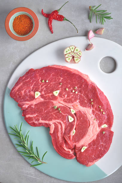 istock Raw steak meat with spices and herbs, flat lay on light stone background 1137138411