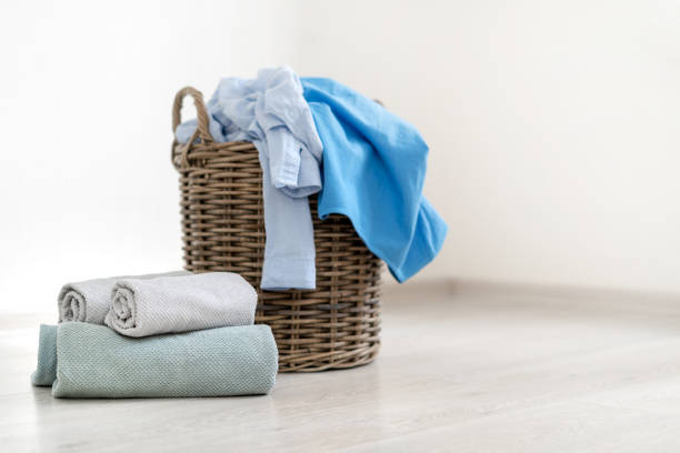 istock Big or large laundry basket with dirty pastel blue clothes standing on room floor inside flat with bright interior near rolled fresh and clean towels 1137139236