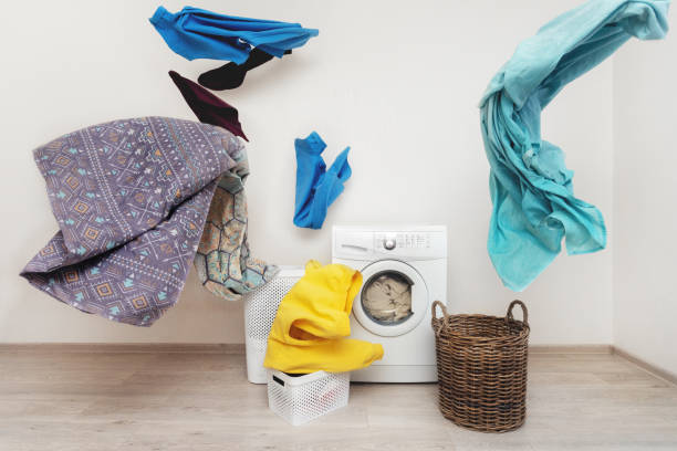 istock Concept of funky and easy laundry process. White washing machine standing inside flat with bright interior near flying multicolored clothes 1137141216