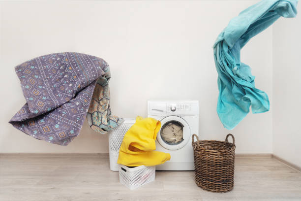 istock Concept of happy and easy laundry process. New modern washing machine standing inside bright apartment light interior with copy space for text near flying multicolored linen 1137141230
