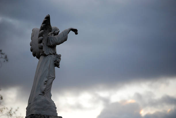 A profile at dusk of a graveyard angel with mountains and church buildings in the backgroundFrom the same subject: