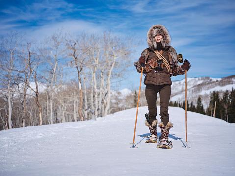 A Japanese woman wearing snowshoes, exploring the winter wilderness in the mountains.