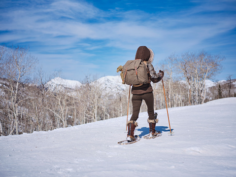 A Japanese woman wearing snowshoes, exploring the winter wilderness in the mountains.