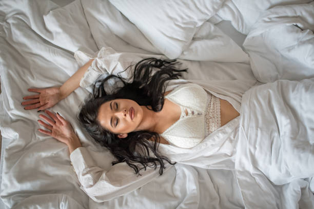 istock Young sexy woman lies on white sheets surface 1137150584