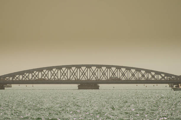 Faidherbe bridge, a metal bridge spaning over the river in Sant Louis, Senegal in an early hazy morning with a car and some people passing over it.