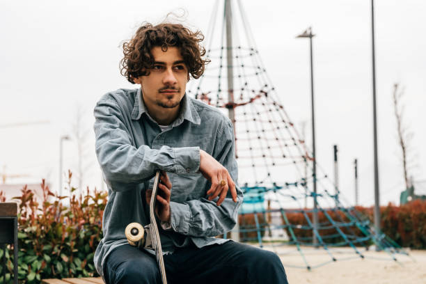 istock Young man sitting and holding skateboard 1137162746