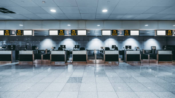 Check-in area of a modern airport Front view of a check-in area in a modern airport: luggage accept terminals with baggage handling belt conveyor systems, multiple empty white informational LCD screen mockups, indexed check-in desks airport check in counter stock pictures, royalty-free photos & images