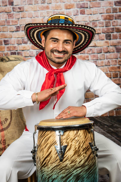 Colombian man playing bongo wearing typical coastal outfit Smiling mid adult Colombian man playing bongo wearing typical valledupar coastal outfit on a brick wall background tropical music stock pictures, royalty-free photos & images