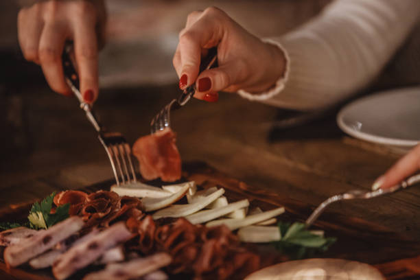 Close-up shot of three women eating delicatessen and cheese at the dining table.