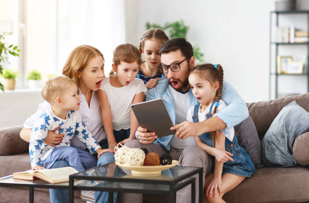 家庭でのタブレットコンピュータを持つ大家族の母、父と子供 - family room ストックフォトと画像