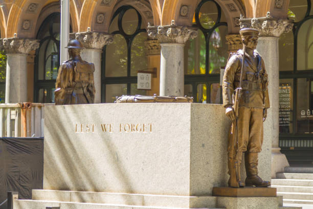 Sydney, Australia - March 17, 2019: The World War ! memorial in Martin Place in Sydney Australia. The Message Lest we forget is clearly seen on the granite block.\n\nStatue of a soldier holding a rifle with a bayonet at the war memorial in Martin Place. Queen Victoria in the back ground.