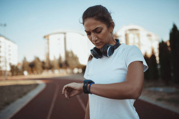 ランニングとトラックフィールドの時間をチェックする女性 - running track women running spring ストックフォトと画像