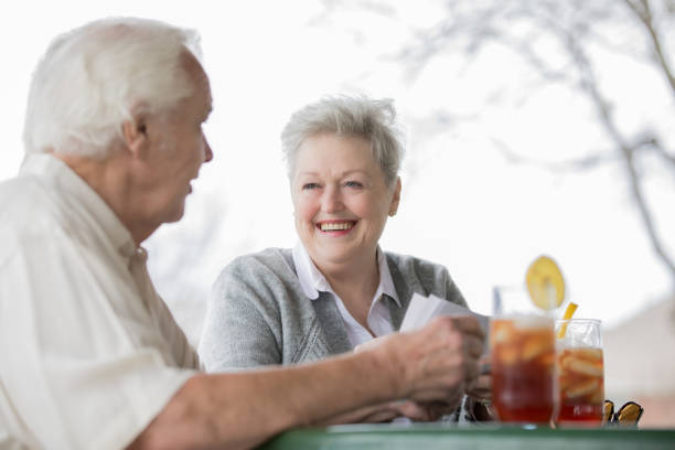 marido y mujer senior riendo juntos mientras mira fotografías y bebiendo té helado - texas tea fotografías e imágenes de stock