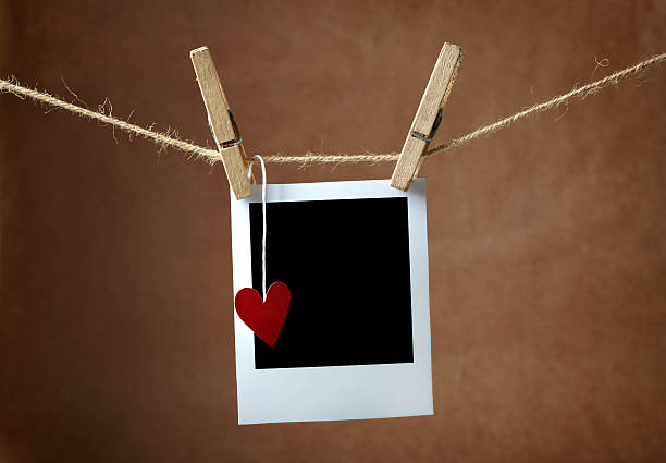 em branco foto frame e pequeno coração pendurado no varal de roupa - love hanging indoors studio shot imagens e fotografias de stock