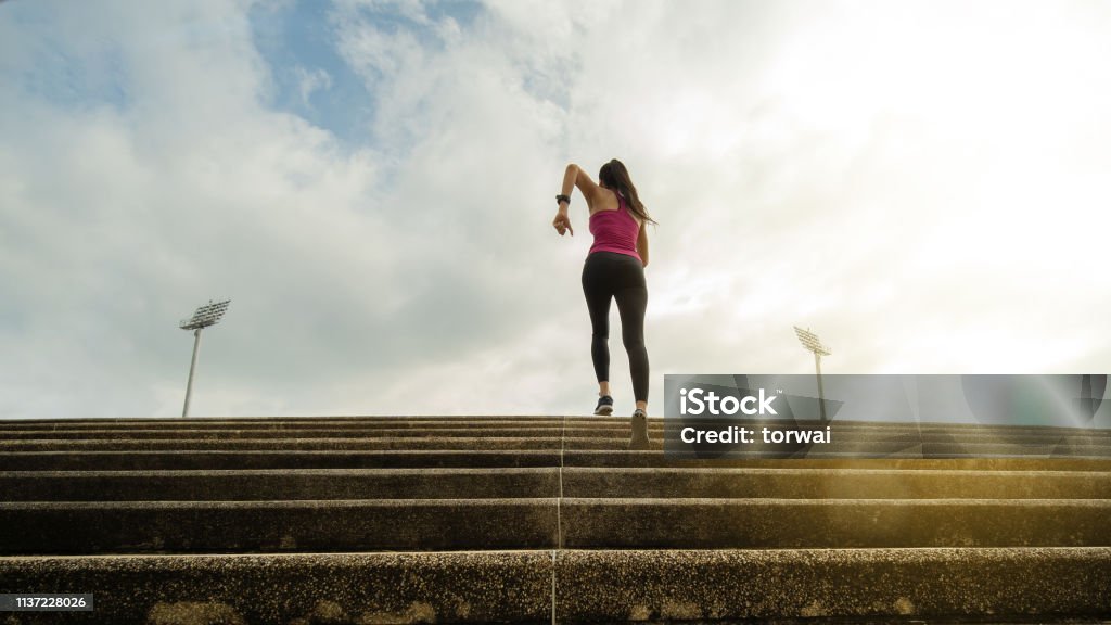 Fitness woman she is running up the stairs. Heat - Temperature Stock Photo