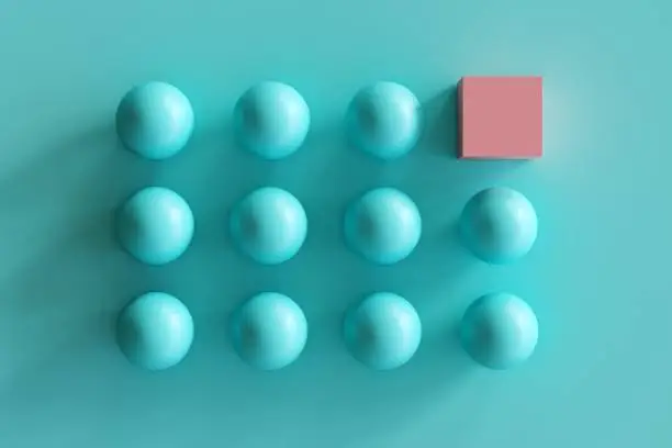 Photo of outstanding pink box among blue spheres on blue background. minimal contept idea