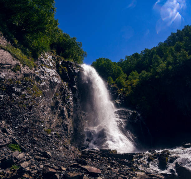 A high mountain waterfall makes its way through huge stones on a clear, summer day. High in the Caucasian mountains, in the outskirts of Dombai.chuhursky waterfall