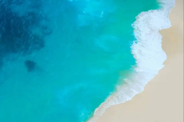 Aerial view of beautiful turquoise sea waves splashing on the shoreline