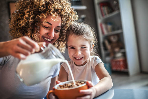 portrait d'adorable jeune fille et mère ayant le petit déjeuner - céréales du petit déjeuner photos et images de collection