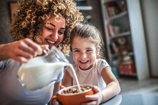 portrait of adorable young girl and mother having breakfast - breakfast family child healthy eating imagens e fotografias de stock