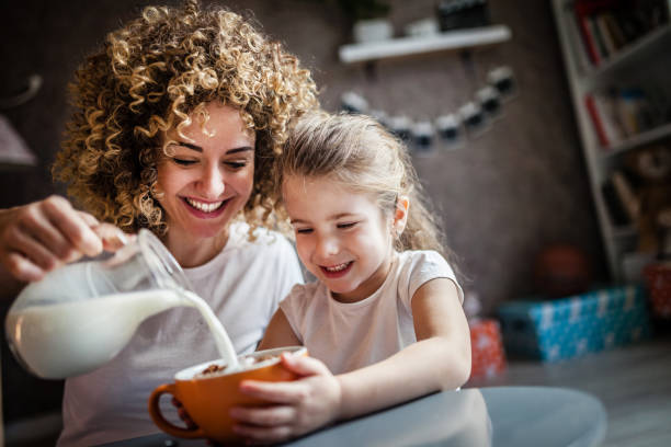 ritratto di adorabile ragazza e madre che colazione - eating women breakfast cereal foto e immagini stock