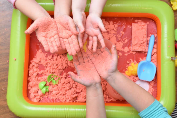 children play with pink kinetic sand for sculpting figures and show their hands. top view, hands close up - sandbox child human hand sand imagens e fotografias de stock