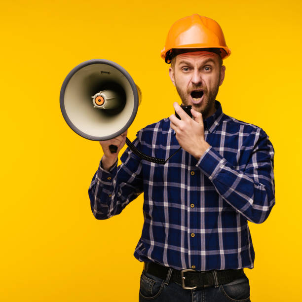 istock Angry worker man with a megaphone on yellow background 1137253687