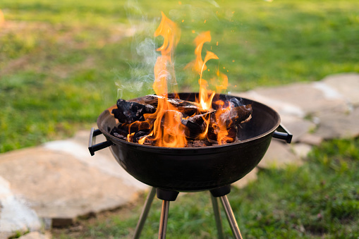 Burning wood in barbecue grill, preparing hot coals for grilling meat in the back yard. Shallow depth of field