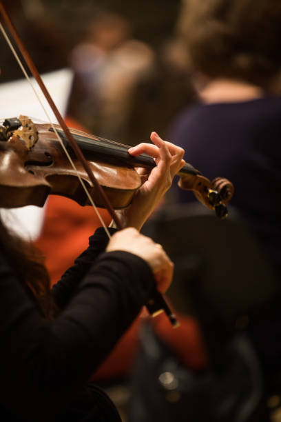 Woman performing on a violin Close up shot of a woman performing on a violin during a concert. symphony orchestra photos stock pictures, royalty-free photos & images
