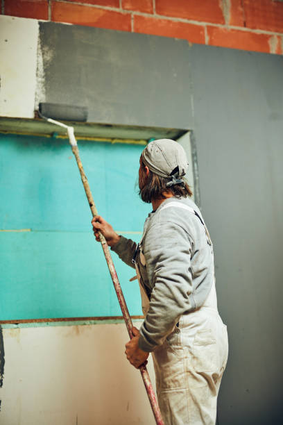 istock Painter painting walls with a extender roller indoors. 1137260146