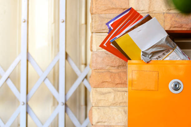 Modern lockable yellow postbox with many mail letter inside. Brick wall and steel doors background.