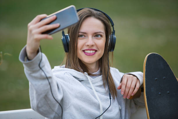 istock Girl with longboard taking selfie in outdoors cafe 1137272236