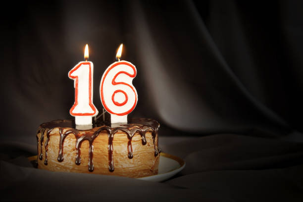 sedici anni. torta al cioccolato di compleanno con candele bianche bruciate sotto forma di numero sedici. sfondo scuro con stoffa nera - 16 foto e immagini stock